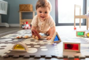 Cute happy baby boy playing toys in his child room
