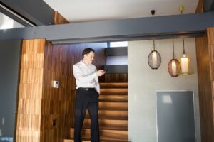 Man controlling home light with digital tablet in interior of modern house.