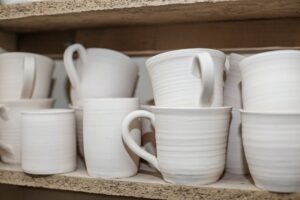 Wooden shelving in pottery workshop, which has pottery standing on shelves in pottery workshop.