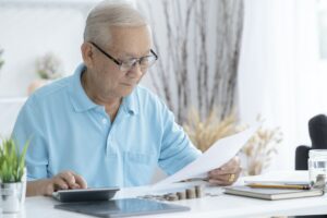 Senior man calculating taxes at home.